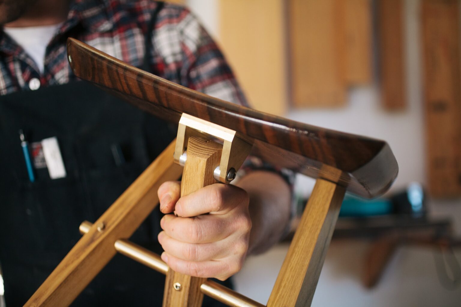 A hand holds the frame of a chair under construction.