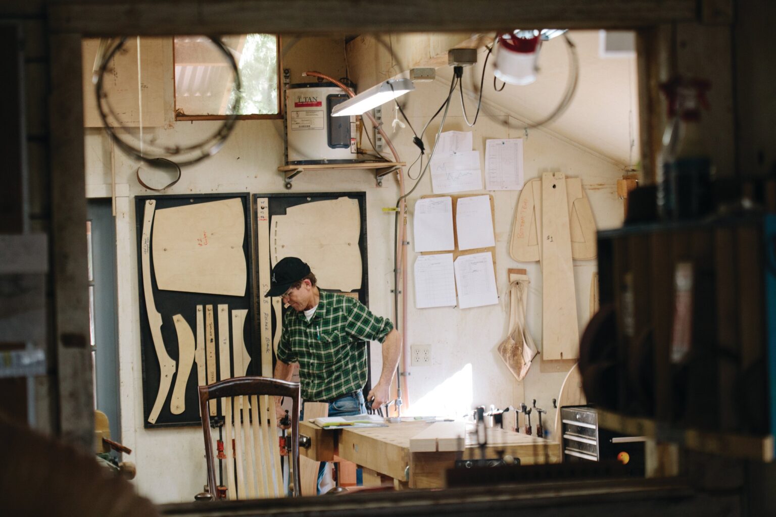 A person works beside chair frames in the workshop.