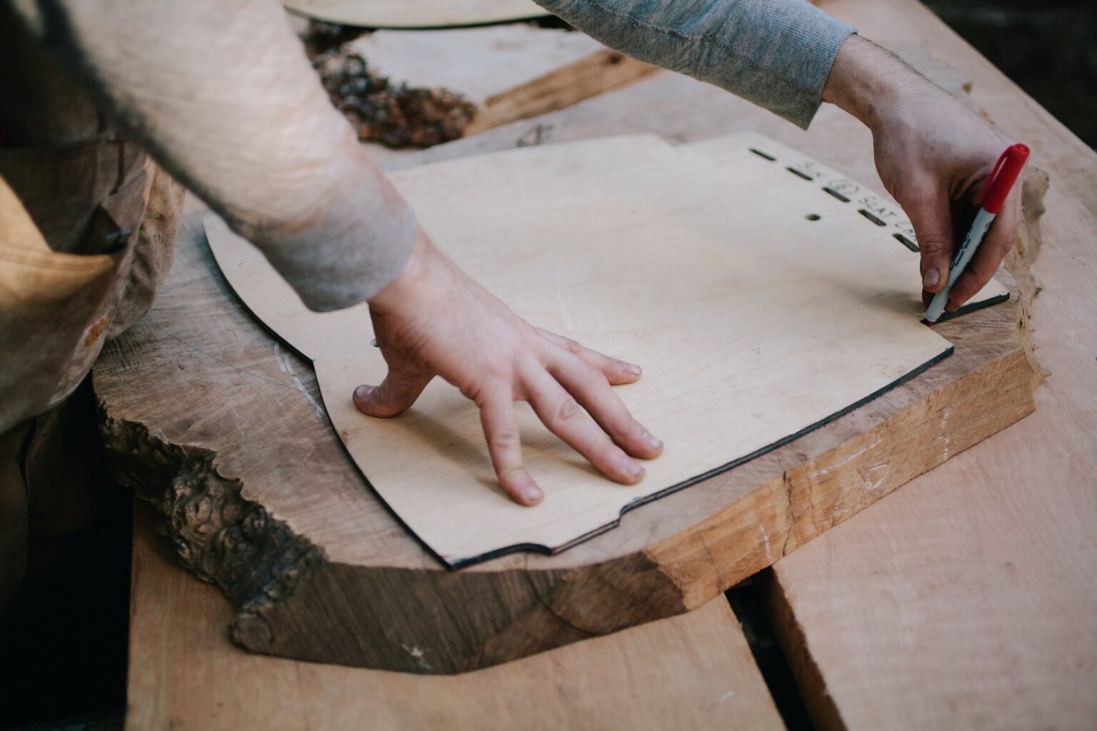 Hands tracing a template onto a wooden board.