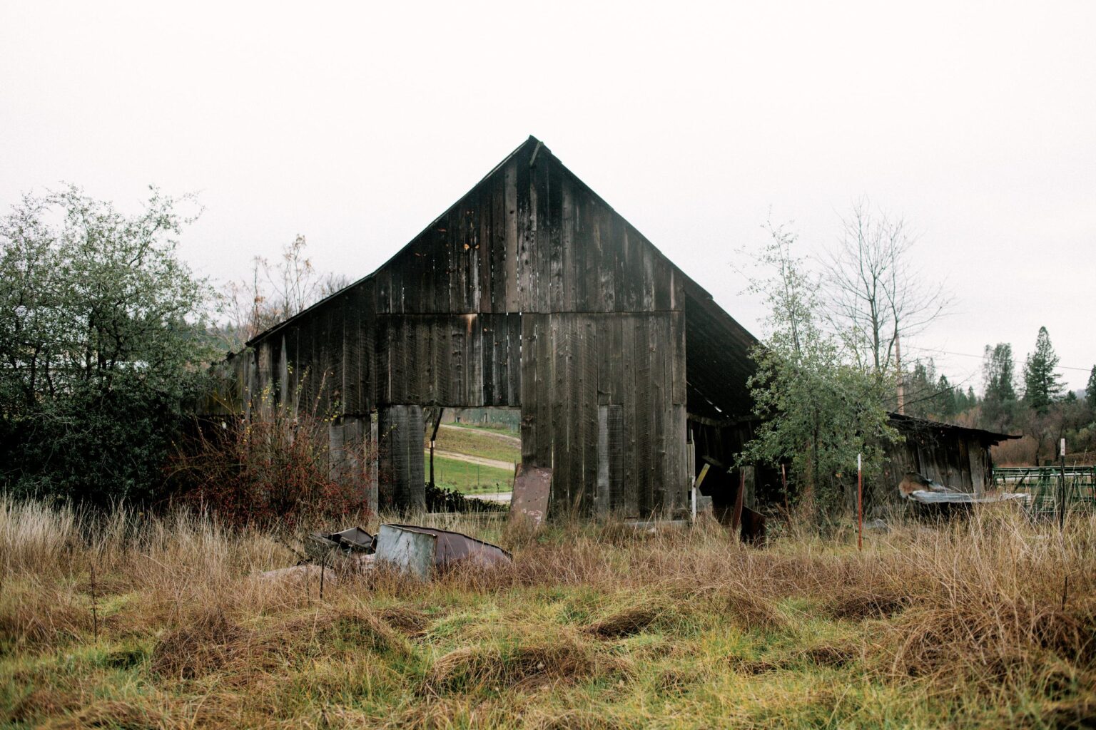A weathered wooden building standing in the grass.